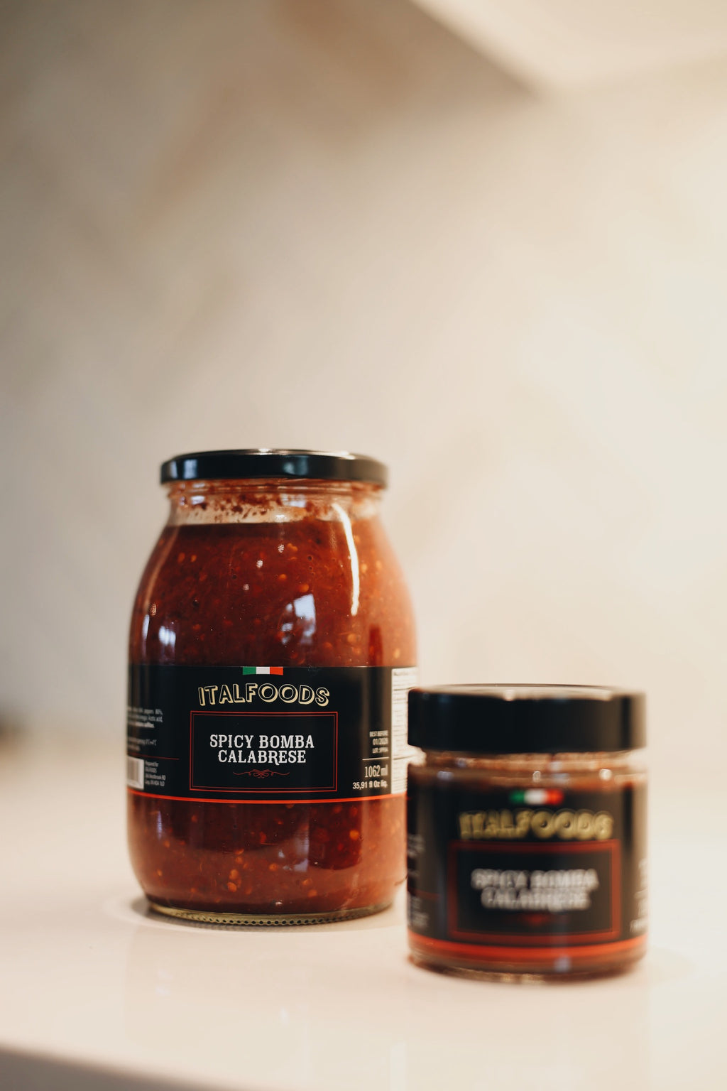 Two jars of Italfoods spicy salsa on a light surface with a neutral background