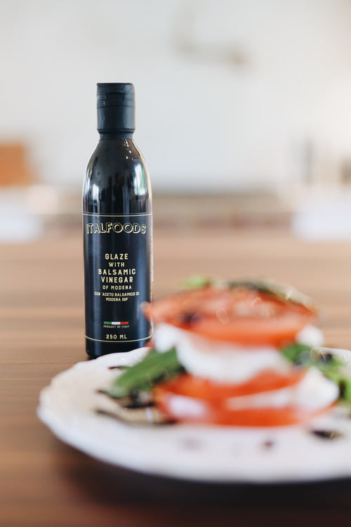 Bottle of Italfoood glaze on a table with a blurred dish in the background